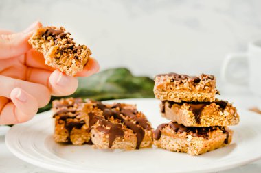 Ham Paleo enerji çubukları sağlıklı fındık ve kurutulmuş meyve ile yapılan. Beyaz mermer masada ev yapımı atıştırmalık. Diyet detoks gıda kavramı... Yeme süreci. Genç bir kadının ellerinde.
