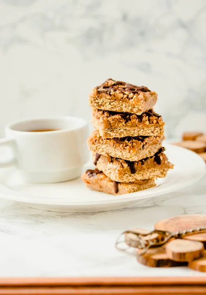 Granola bar with date caramel and chocolate. Healthy sweet dessert snack. Cereal granola bar with nuts, fruit and berries on a white marble table.Copy space for text.