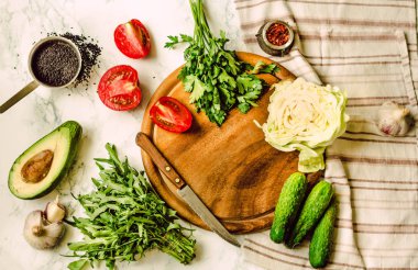 Yeşillik, domates, salatalık, baharat, avokado, sebze, bahar taze yiyecek. Ham salata hazırlanıyor. Ahşap masa, üstten görünüm. Sağlıklı yaşam tarzı ve dengeli gıda kavramı
