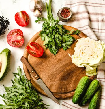 Yeşillik, domates, salatalık, baharat, avokado, sebze, bahar taze yiyecek. Ham salata hazırlanıyor. Ahşap masa, üstten görünüm. Temiz diyet yemek. Diyet gıda kavramı. Sağlıklı gıda arka plan.