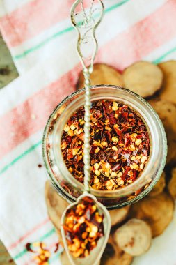 Yere dökülen cam can ve rustik kaşık biber kurutulmuş. Ezilmiş biberler. Üstten görünüm.