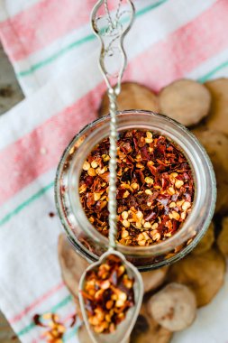 Yere dökülen cam can ve rustik kaşık biber kurutulmuş. Ezilmiş biberler. Üstten görünüm.