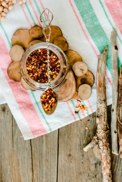 Ground dried chili pepper spilled from glass can  and rustic spoon. Crushed chillies. Top view.Copy space for text.