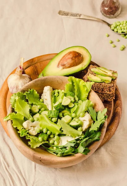 Frischen köstlichen grünen Salat mit Avocado in einem Holzteller und g — Stockfoto