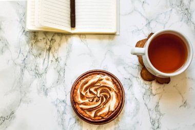 Boş not defteri, bir fincan çay ve kek. Kopyalama alanı ile üstte görünüm