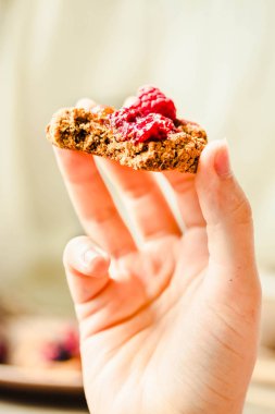 Elinde ahududu reçeli ve hurma ile yulaflı kurabiye