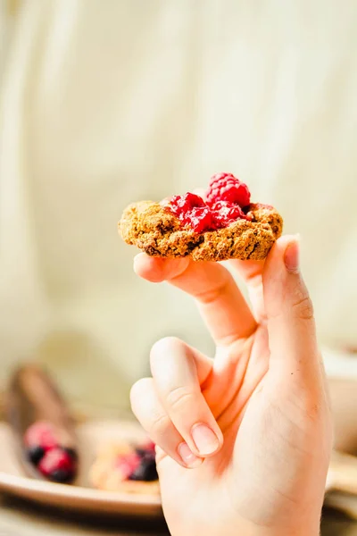 Galletas de avena con mermelada de frambuesa y caramelo de fecha en las manos — Foto de Stock