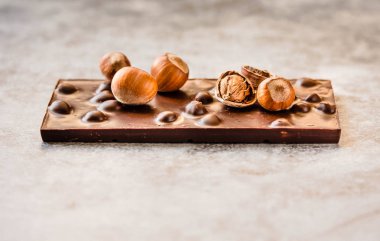 Gri backgroun üzerinde kabuk fındık ile Koyu çikolata bar