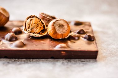 Gri backgroun üzerinde kabuk fındık ile Koyu çikolata bar