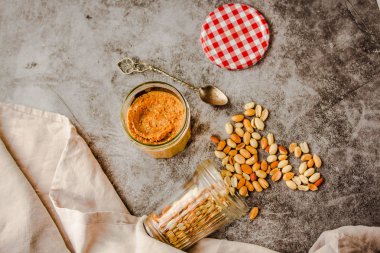 Koyu ahşap arka plan müziği üzerinde fıstık ezmesi ve fıstık kavanoz ve kaşık