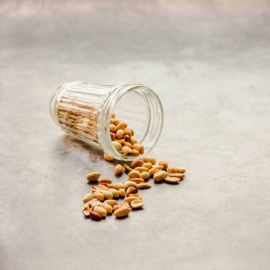 Gri arka planda bir camdan kavrulmuş fıstık.