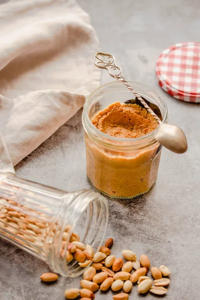 Cremige und glatte Erdnussbutter im Glas auf grauem Tisch. natürliche nu — Stockfoto