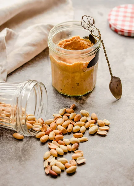 Frische hausgemachte cremige Erdnussbutter in einem Glas auf grauem Backblech — Stockfoto