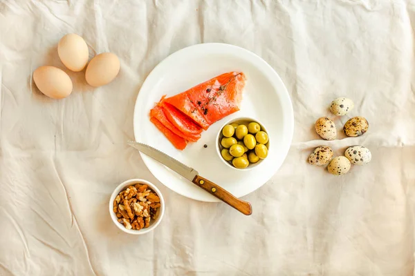 Salt Salmom with quail eggs, nuts and olive on a white linen tab — Stock Photo, Image