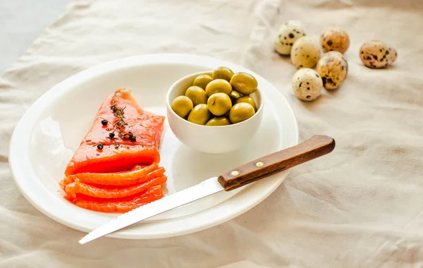 Rodajas de filete de pescado crudo salado con aceituna, huevos de codorniz sobre blanco —  Fotos de Stock