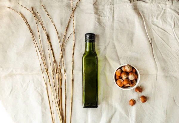Natives Haselnussöl extra in einer grünen Glasflasche und grünem Olivenöl — Stockfoto