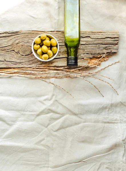 Aceite de oliva virgen extra en una botella de vidrio verde y aceitunas verdes . — Foto de Stock