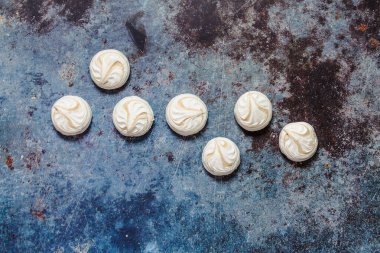 Mavi metal arka planda beyaz marşmelov ve kahve.