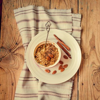 Meyveler ve fındıklar cam bir kase içinde turta sunucusu ve bir fincan siyah çay veya ahşap bir masada kahve. Sağlıklı bir tatlı ya da sonbahar sabahı kahvaltısı konsepti. Üst görünüm. Insta boyutu.
