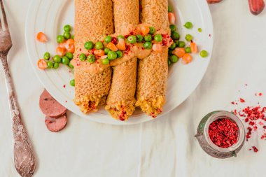 Soslu karabuğday ve nohut undan yapılmış vejetaryen krepleri, kırmızı biber, tatlı mısır ve yeşil bezelye..