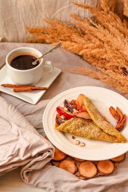 Şeftalili, bademli ve tatlı meyveli glütensiz keto krepleri. Tarçınlı bir fincan kahve. Seçici odaklanma. Sonbahar sağlıklı kahvaltı ya da tatlı konsepti.