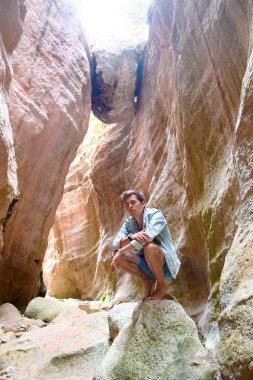 Bir taş Kanyon oturan adam gezgin. Yaban hayatı. Taş kemerli duvar. Adam üzerinde tökezleyerek yazıyor. Afrika Safari. Güney doğa. Macera arayışı içinde bir gezgin.