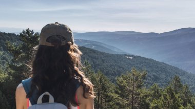 Şapkalı genç kadın doğayı düşünüyor.