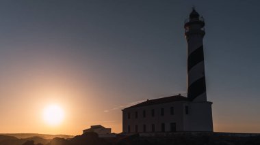 Gün batımında bir uçurumun kenarında deniz feneri