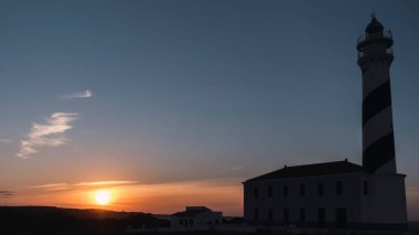 Gün batımında bir uçurumun kenarında deniz feneri