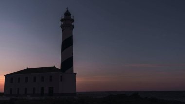 Gün batımında bir uçurumun kenarında deniz feneri