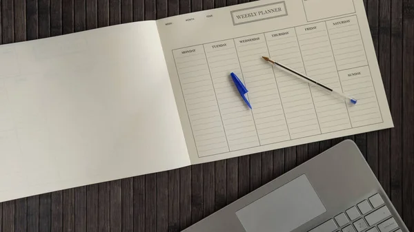 Planner book and calendar concept.Weekly planner, pen and laptop