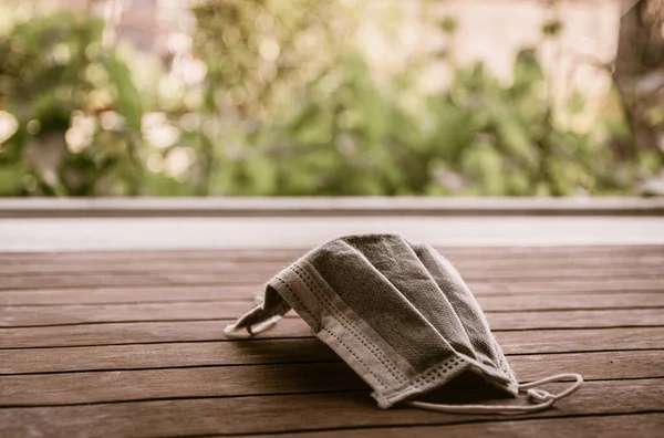 Tahta masada tek kullanımlık bir maske, izole, açık havada doğal bir yerde, yeni normallik kavramı, her yerde maskeler.. 