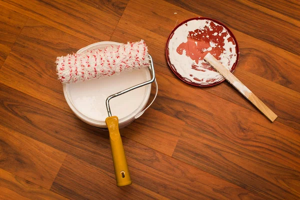 Beyaz duvar boyası kovasında boya silindiri ahşap parke zeminde kal, kuş bakışı görüş, izole edilmiş.