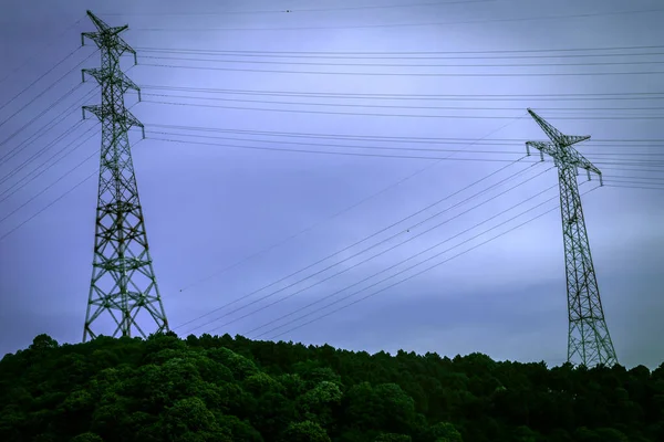 Şehrin dev metal kulelerdeki ana güç hatları. Koyu mavi gökyüzü ve gece beyaz bulutlarla dramatik bir atmosfer. orta büyüklükte genel plan.