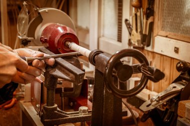 Ahşap işçisi torna tezgahında bir parça odun şekillendiriyor, ahşap dönüyor. yakın plan görünümü.  