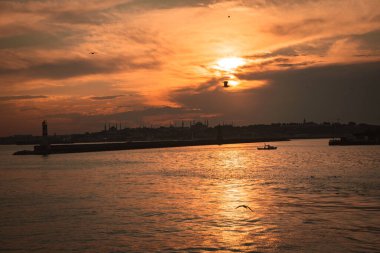 Gün batımında bir deniz feneri. Şehir manzaralı..