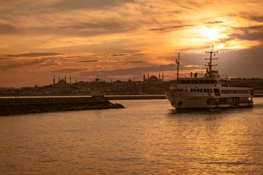 Şehir hatları yolcu gemisi gün batımının güzel bir anında yola çıkıyor. İstanbul 'un arkasında yaz manzarası var..
