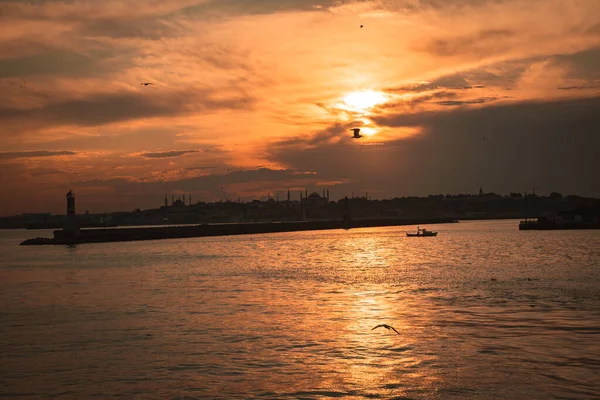 Gün batımında bir deniz feneri. Şehir manzaralı..