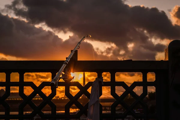 Gün batımında köprüye bağlanmış bir olta kamışı.