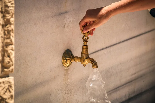 Antik bir bronz çeşmeden akan su bir kadın eliyle açıldı. yakın plan.