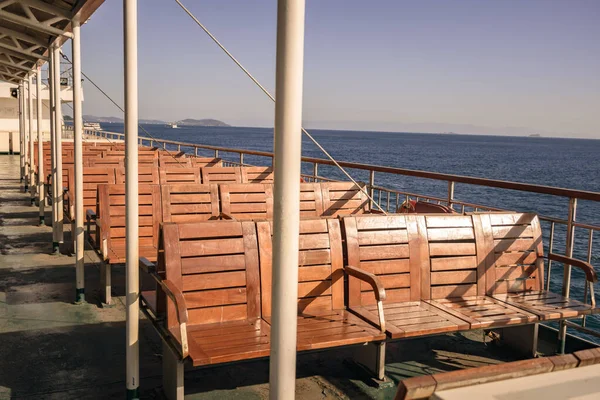 Feribot terasında boş koltuklar, arka plan olarak mavi gökyüzü ve deniz..