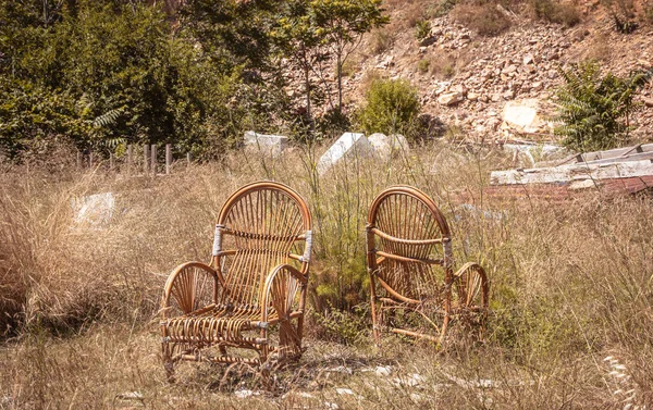 wicker chairs abandoned in a natural field, general plan with outdoor nature background.