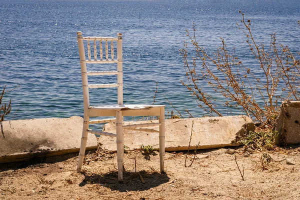 Eski ahşap bir sandalye deniz kenarında izole bir şekilde duruyor..