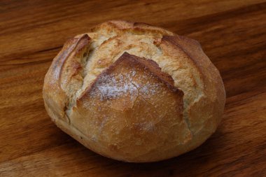 Kahverengi ahşap platformda, yakın plan, kalın hamurlu, organik yuvarlak köy ekmeği..