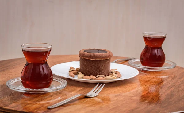 İki bardak geleneksel Türk çayı ve ortada da ahşap masada servis edilen çikolatalı kek..