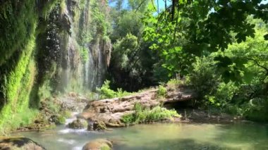 Türkiye 'nin Antalya kentindeki ünlü Kursunlu şelalesi, güneşli bir günde yeşil bitkiler ve çiçeklerle çevrili. 4k stok video.