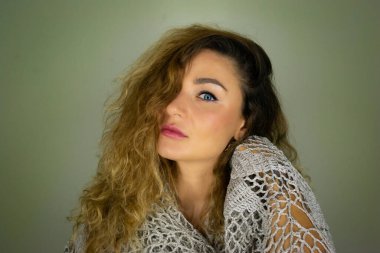 Yeşil yapraklı kıvırcık saçlı, mavi gözlü güzel bir kızın yarım portresi. Resim yükle.