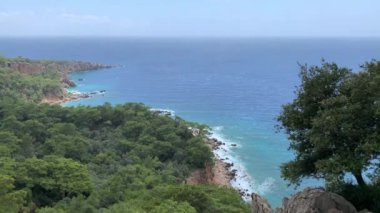 Güneşli bir günde Akdeniz 'in, dağların ve çam ağaçlarının olduğu vahşi sahillerin manzarası. 4k video.