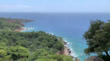Güneşli bir günde Akdeniz 'in, dağların ve çam ağaçlarının olduğu vahşi sahillerin manzarası. 4k stok video.