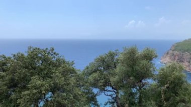 Güneşli bir günde Akdeniz 'in, dağların ve çam ağaçlarının olduğu vahşi sahillerin manzarası. 4k video.
